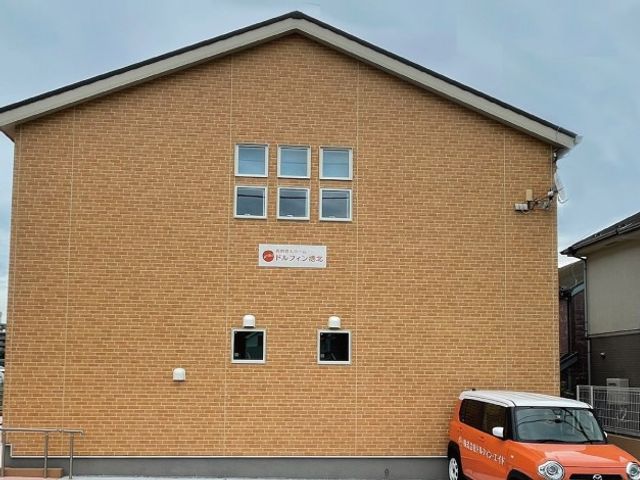 建物正面の外観 外観   レンガ調の外壁が印象的な建物の正面です。看板が掲げられ、車の出入りもしやすそうなつくりです。
