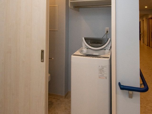 洗濯機と棚の設備 洗濯機 便利な洗濯設備が整った快適な空間です。ご利用者様の日常生活に寄り添った設計をご覧いただけます。