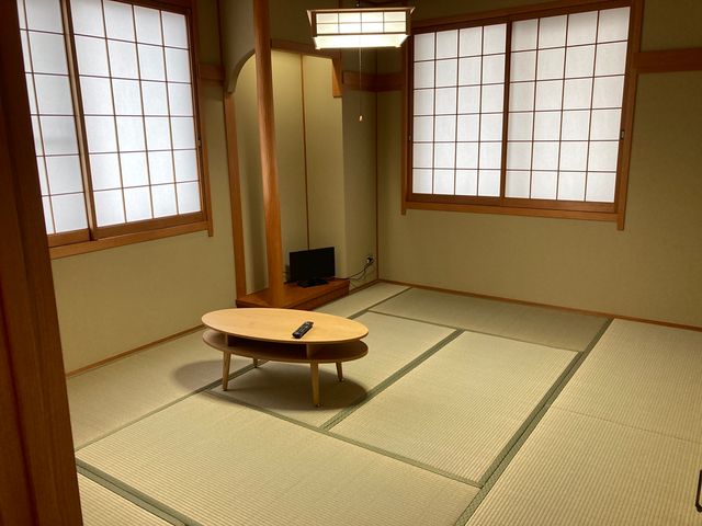 清潔な和室の居室 居室 和の趣ある落ち着いた空間で、ゆったりと過ごすことができます。日本式の畳が敷かれ、テーブルとテレビが置かれている様子が映っています。