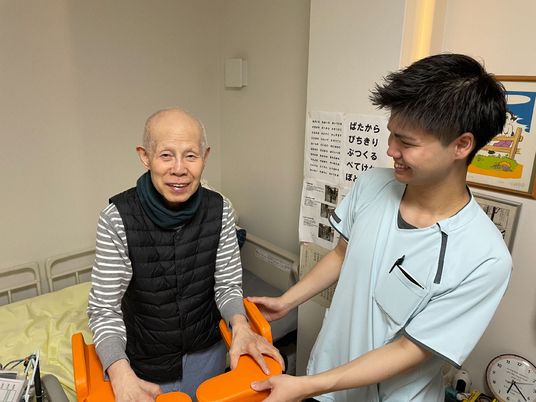 笑顔でリハビリする高齢者と職員