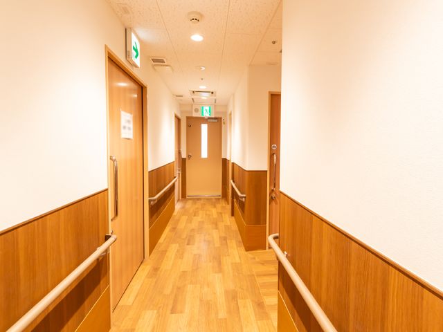 明るく清潔感のある廊下 廊下 手すりが設けられた廊下は安全かつ快適に移動でき、壁面と床の色合いが温かみを演出しています。