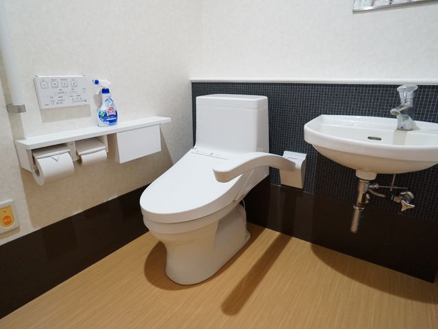 バリアフリー対応トイレ トイレ 手すり付きの洗練されたデザインのトイレです。安全かつ快適な利用をサポートする工夫がされています。