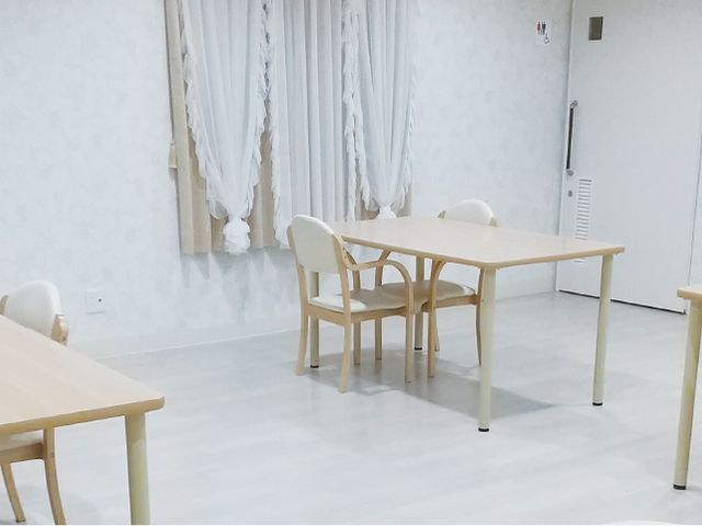 明るい居室の一角 居室 ゆったりとした木のテーブルが配置され、穏やかな雰囲気の個室です。周囲には余裕のあるスペースが確保されています。
