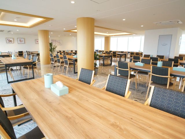 広々とした明るい食堂 共有スペース 広くて明るい共有食堂です。温かみのある木材を使ったテーブルやイスが配置され、皆で食事を楽しめる環境が整っています。