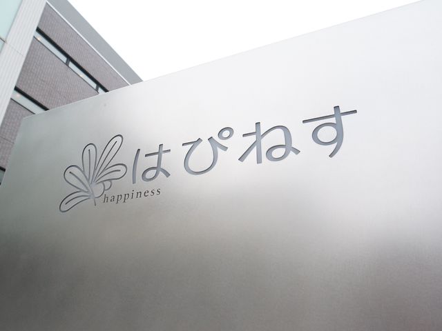 施設のシンプルな看板 玄関 清潔感あふれるシンプルなデザインの看板です。日々の業務において、明るい印象を与える環境が整っています。