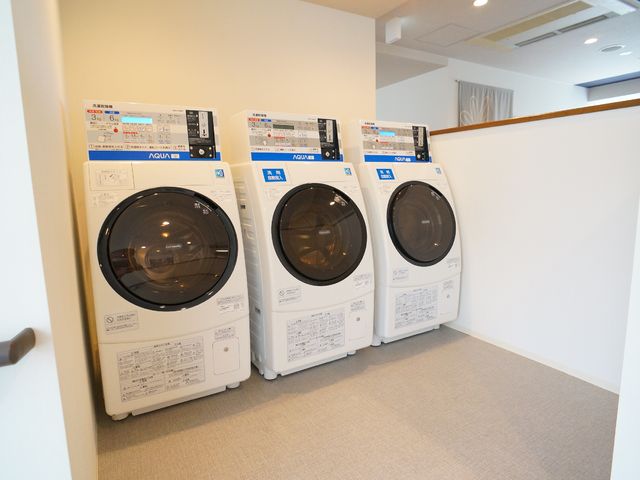 清潔な洗濯機並ぶ空間 共有スペース 最新の洗濯機が整然と配置され、快適な洗濯環境が整備されています。毎日の生活に便利さをプラスしています。