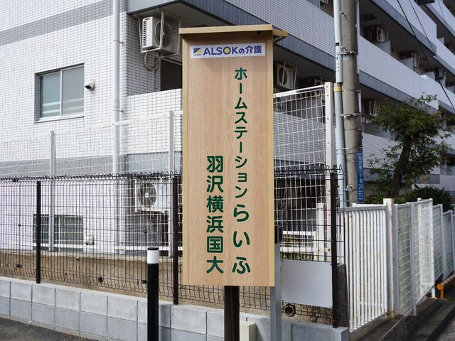 案内看板 ロゴ 清潔感がある外観を背景にした案内看板です。働く環境の第一印象として、安心感を与える明朗な入口がお迎えします。