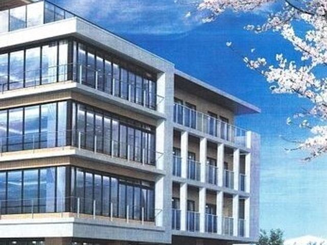 桜並木に隣接する施設外観 外観 春の訪れを感じさせる桜と調和する、モダンなデザインの建物です。清潔感あふれる環境で働くやりがいを感じていただけるかと思います。