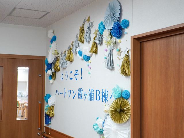 壁飾り付きの部屋の入口 飾り付け ハンドメイドの壁飾りが温かな雰囲気を醸し出すエントランスです。明るい笑顔で新たな仲間をお待ちしています。