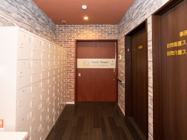 廊下にロッカーと扉 玄関 落ち着いた雰囲気の廊下には整然と配置されたロッカーがあり、職員スペースへとつながる扉も見えます。安心して業務に励める環境です。