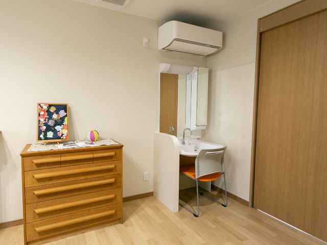 快適な居室 洗面台 広々とした居室には、清潔な洗面台が備え付けられ、生活に必要な家具も整っています。個々の生活スタイルに合わせた空間作りが可能です。
