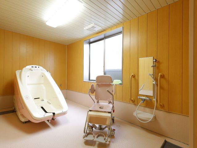 清潔な介護用浴室 機械浴 木目調の壁に囲まれた明るく清潔感ある浴室です。バリアフリー設計で安心してご利用いただけます。