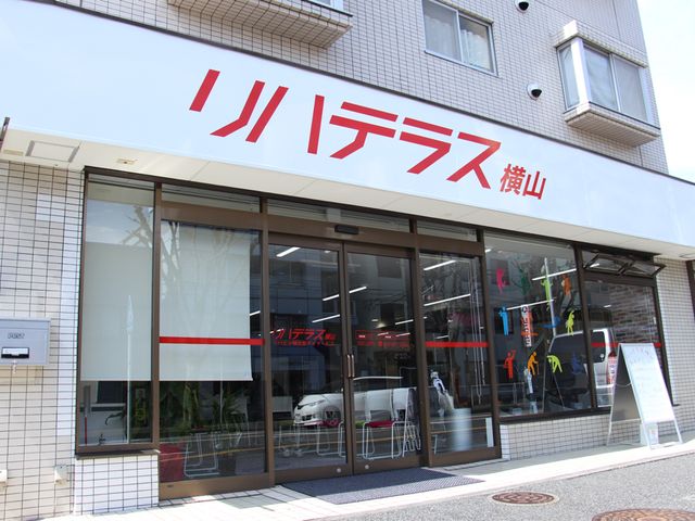 入口と看板の風景 エントランス エントランスの大きなガラスドアが開放的です。施設の名前がはっきりと表示されています。