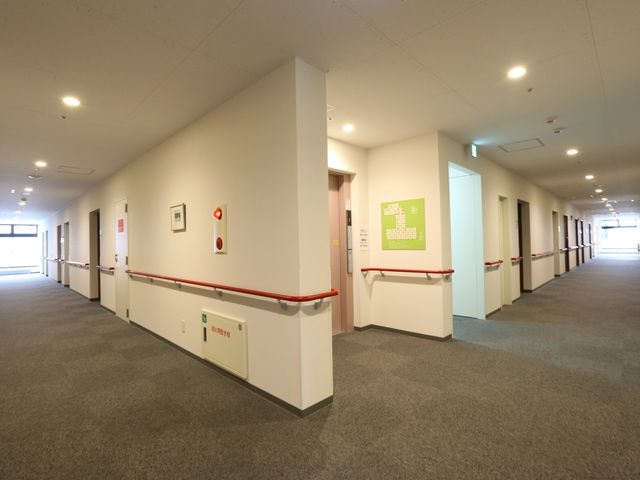 広々とした明るい廊下 通路 手すり付きの清潔感のあふれる廊下が、日々の業務をサポートします。周囲は明るく、清潔で落ち着いた雰囲気が漂っています。