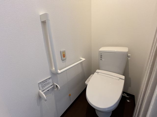 手すり付きのトイレ トイレ 安全を考慮し、手すりを設置したトイレです。利用者の方が安心して使用できる設計になっています。