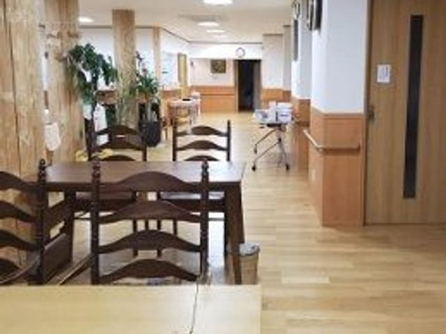 広い会議室のリビング リビング 広々とした明るい空間で、木製の家具と植物が心地よさを感じさせます。