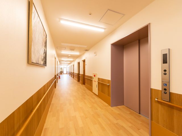 広々とした明るい廊下 エレベーター 温かみのある木目調のバリアフリー設計の廊下は、快適にお過ごしいただける設計です。安心して移動できるよう手すりが整備されています。