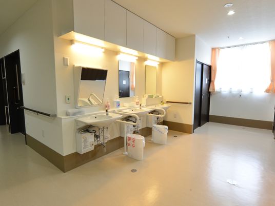 廊下からオープンなっている明るい雰囲気の洗面スペースには手すりが取り付けてあり、3台の洗面台が設置されている。