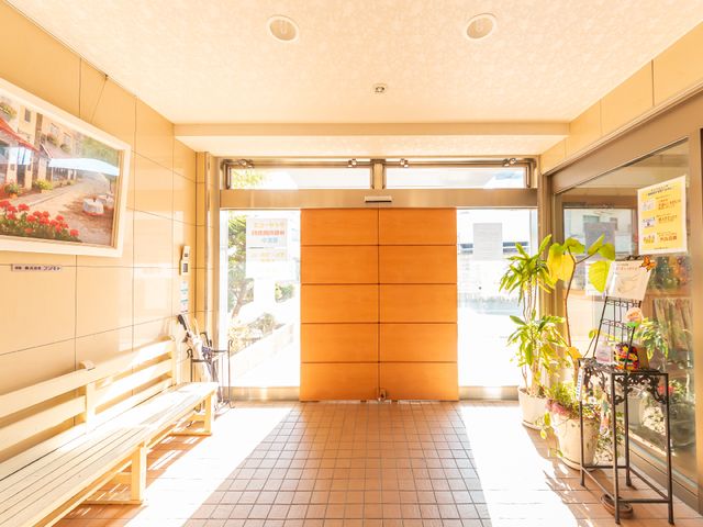 明るいエントランスの風景 玄関 陽光溢れる広々とした入口です。安らぐ緑も取り入れた設計になっており、訪れる方々を温かく迎え入れます。