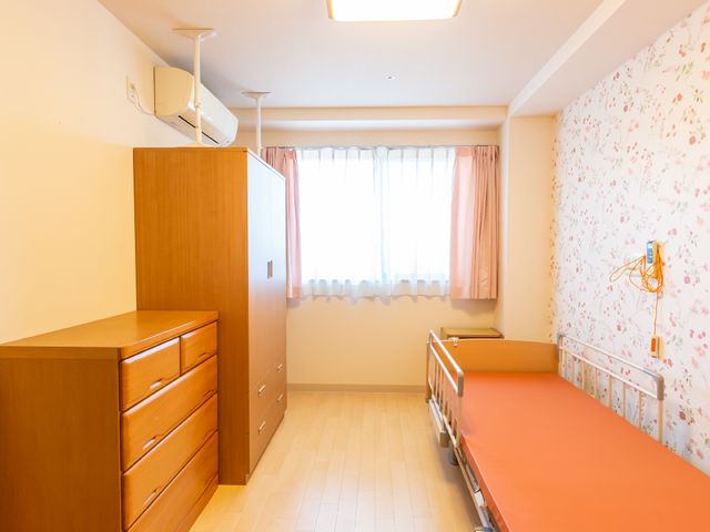 暖かみのある居室の内観 居室 ゆとりある空間で安心の生活を。明るい壁紙と木目調の家具が心地よい雰囲気を演出しています。