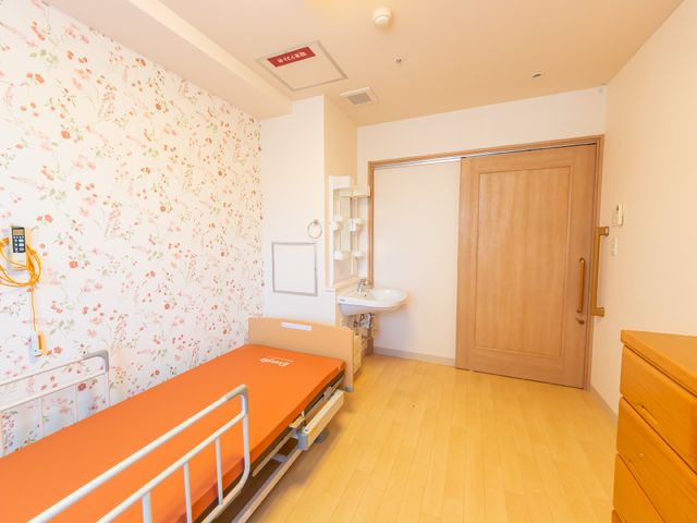 明るく清潔な居室空間 居室 花柄の壁紙が特徴の居室には、必要な設備が整い、快適な生活をサポートします。機能的な家具配置で、ゆったりとお過ごしいただけます。