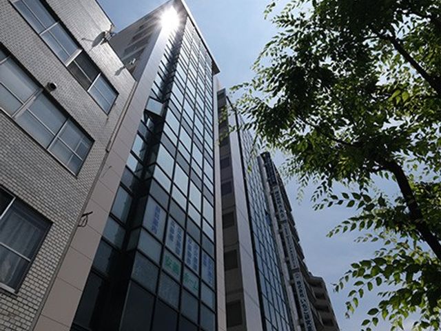 高層ビルの外観 外観 高層ビルの外観が空に向かって伸びており、周囲には緑が広がっています。