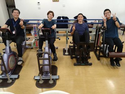 笑顔のスタッフと装置のある機能訓練室