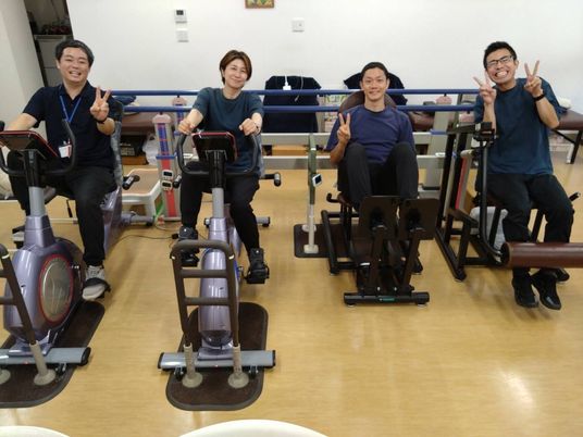 笑顔のスタッフと装置のある機能訓練室