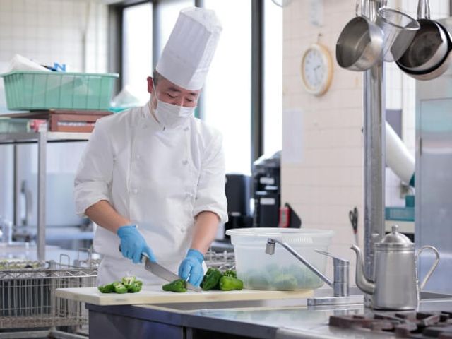 調理するシェフの厨房 キッチン 広々としたキッチンで、調理スタッフが作業しやすい環境です。新鮮な食材を丁寧に扱います。