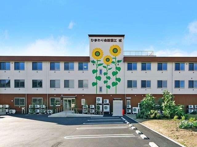 明るい外観の施設入口 外観 清々しい朝日に輝く入口は、来訪者を暖かく迎えます。清潔感溢れる外観が、安心感を与える空間です。