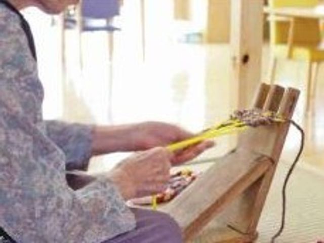 織り機を使う高齢者 レクリエーション 手先を巧みに動かし、創作活動を楽しむ利用者の姿が印象的です。こちらで様々なレクリエーションを提供しております。