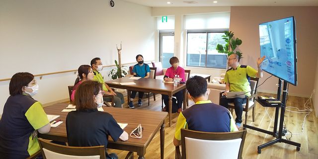 スタッフイメージ リビング ミーティングを行う様子が見られます。自然光が入る明るい空間で、快適に過ごせます。