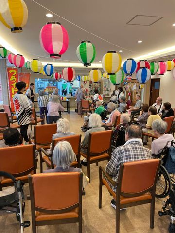 和やかなイベントのラウンジ ラウンジ 多彩な色の提灯が飾られた明るいラウンジです。入居者がレクリエーションを楽しむ様子が見られます。