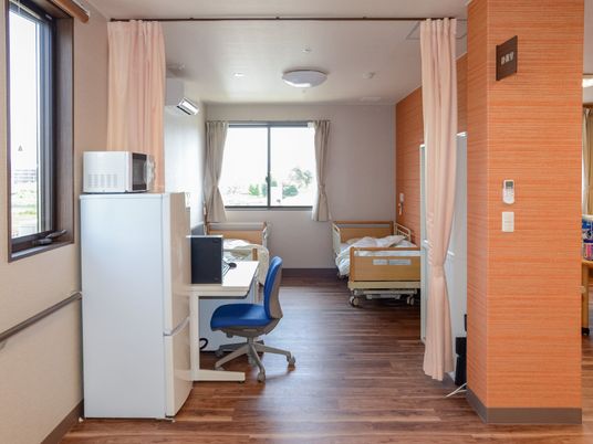 ドアの代わりにオレンジのカーテンが付いている部屋にはベッドが2台置かれ、近くにスタッフ用の椅子がある。