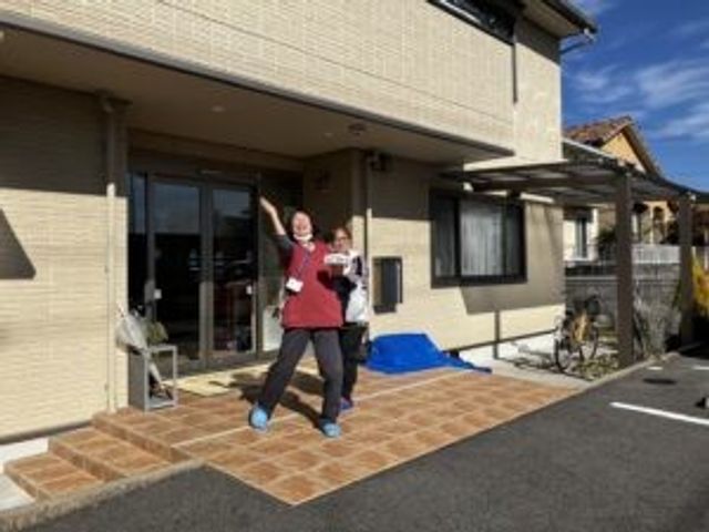 外観前の人物 外観   日差しの入る玄関前で、スタッフらしき方が笑顔で手を振っています。明るい外観で、出入りの様子が伝わります。