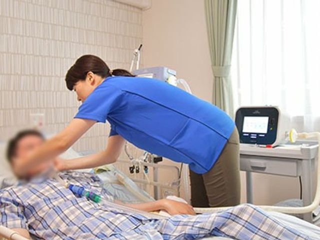 看護師による介助の居室 居室 日差しが差し込む居室では、丁寧な介助が行われています。リラックスできる環境です。