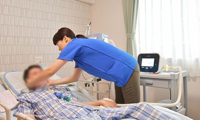 看護師による介助の居室 居室 日差しが差し込む居室では、丁寧な介助が行われています。リラックスできる環境です。