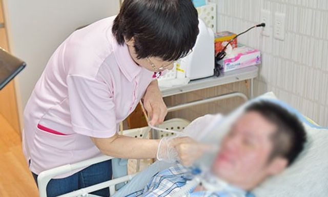 リビングの介護風景 居室 広々とした居室で、介護職員が丁寧にケアを行っています。暖かい雰囲気の空間です。