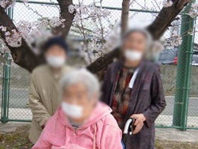 春の団らん 中庭 春の日差しの中で、利用者の方々が桜を楽しんでいます。自然の中での交流が豊かです。