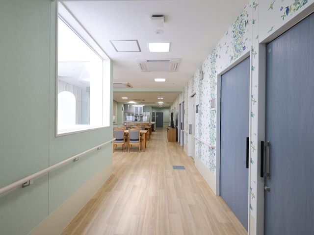 廊下と食堂のある空間 廊下 ゆとりある廊下は、暖かみのある木目調で、壁には花柄の飾りが施されています。先の食堂にはテーブルが設置されており、開放感のある作りです。