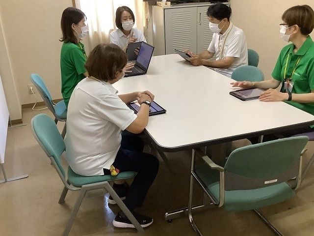 スタッフ会議室 スタッフイメージ スタッフが集まり、意見交換を行っています。コミュニケーションが活発な職場です。