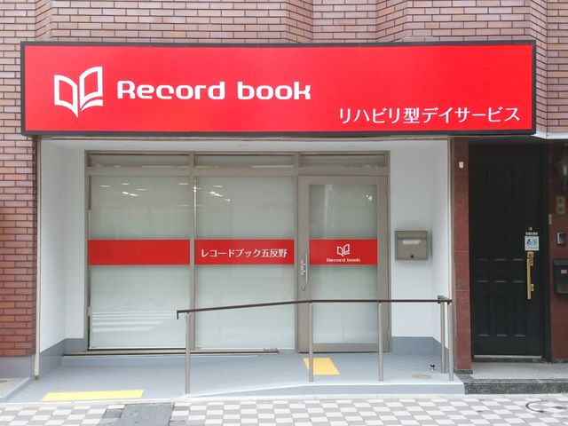赤い看板の入口 看板 リハビリ型デイサービスの入口です。段差のないスロープがありますので、安心して出入りできます。