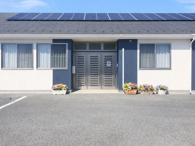 ソーラーパネルのある建物正面 外観 広々としたエントランスには、季節の花が並び、心地よい空間を作り出しています。