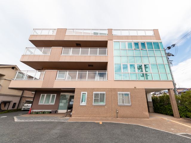 広々とした建物の外観 外観 モダンなデザインが特徴の建物で、広い窓からは明るい陽光が差し込む様子がうかがえます。包括的なケアを目指す方に適した環境です。