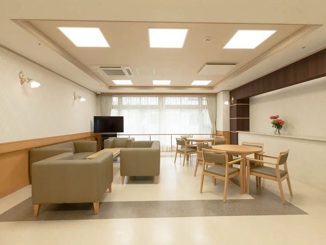 明るい共有ラウンジ リビング   大きな窓から光が入る、ゆったりしたリビングです。ソファ席とテーブル席があり、くつろぎや会話の場として使いやすそうです。