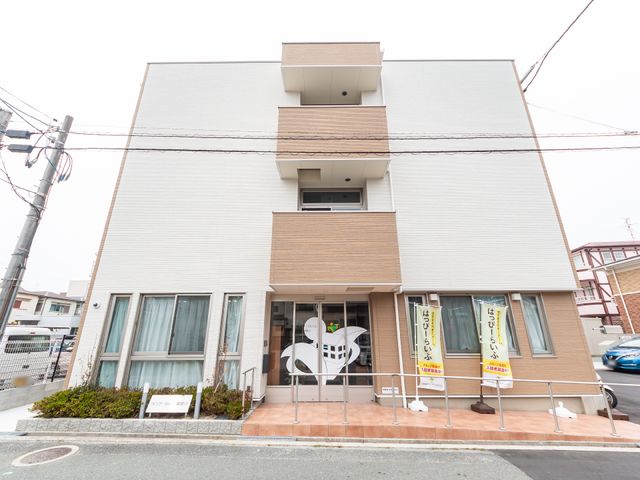 白と茶の建物正面 外観 ゆったりとしたバリアフリー設計の入口が特徴的な、清潔感溢れる建物です。キャリアアップを目指す方にも、快適な就業環境を提供します。