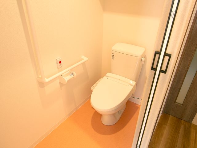 バリアフリー設計のトイレ 居室 安全に配慮された手すり付きの清潔なトイレです。日々の業務を通じて、心地よい環境を支えるお手伝いができます。