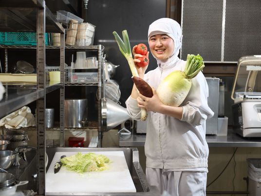 野菜を持つ笑顔の厨房スタッフ