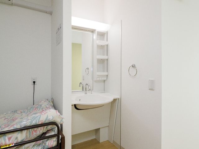 シンプルな居室の角度 洗面台 快適な個室で、ベッドと洗面台が備え付けられています。清潔感溢れる空間が、日々の生活を支えます。