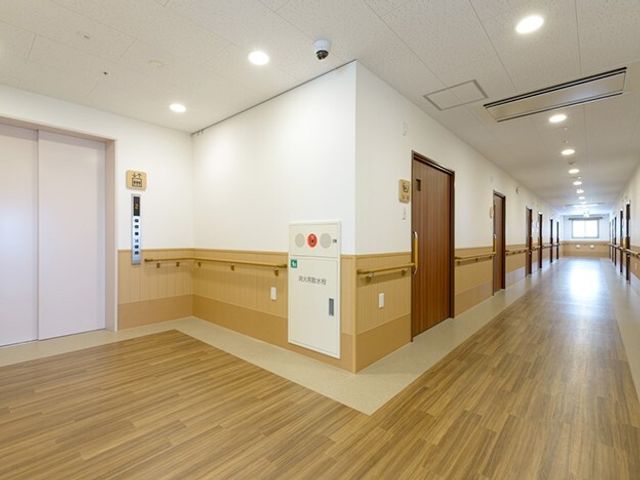 清潔な施設の廊下 ２階ホール 手すり付きの明るい廊下が整備されており、安心して歩行できる環境が整っています。スムーズな移動を支援する広々とした空間です。